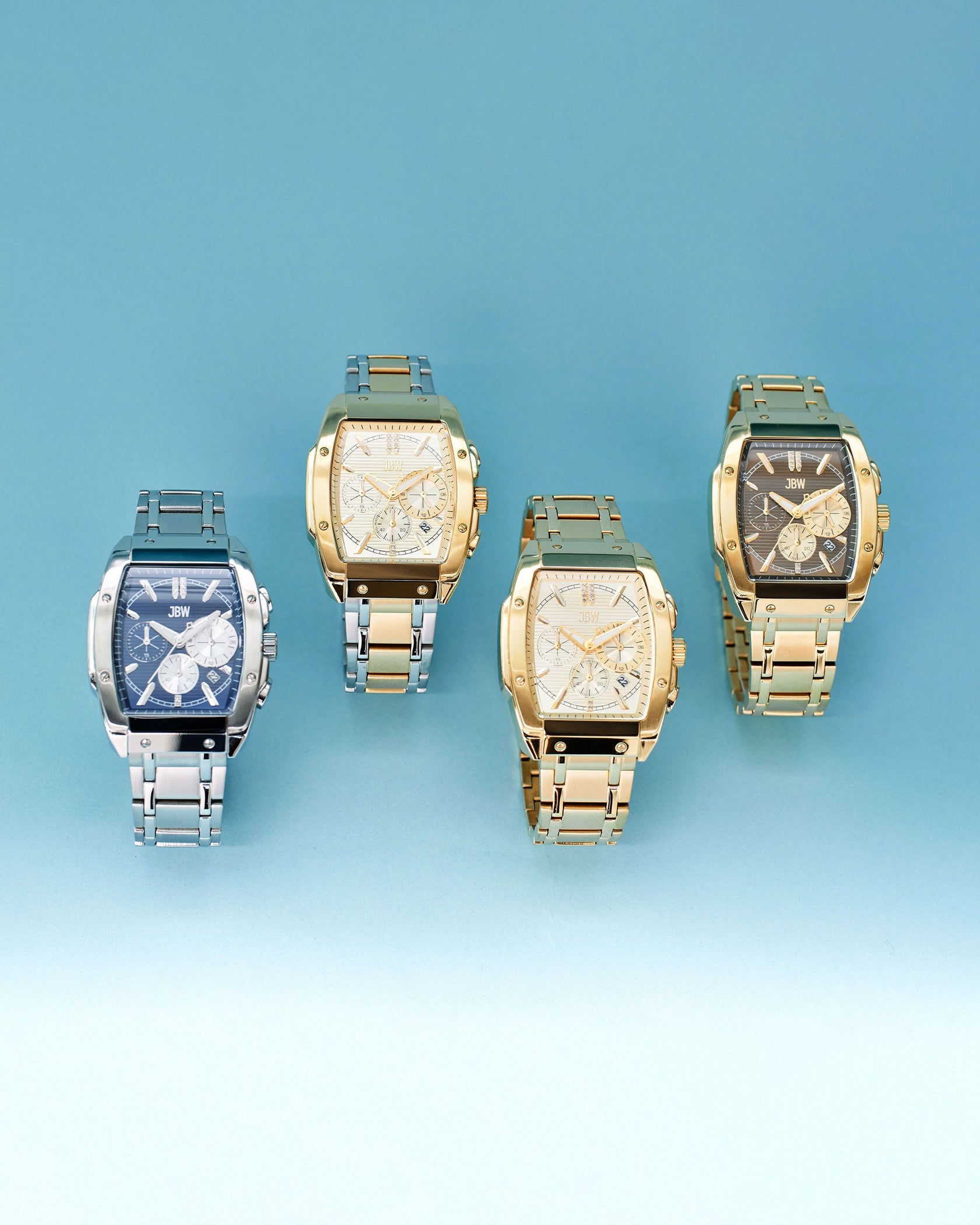 Four JBW Watches Echelon | J6409C wristwatches are displayed against a blue gradient background: two with stainless steel bands and two with 18K gold-plated bands, each featuring a unique watch face design.