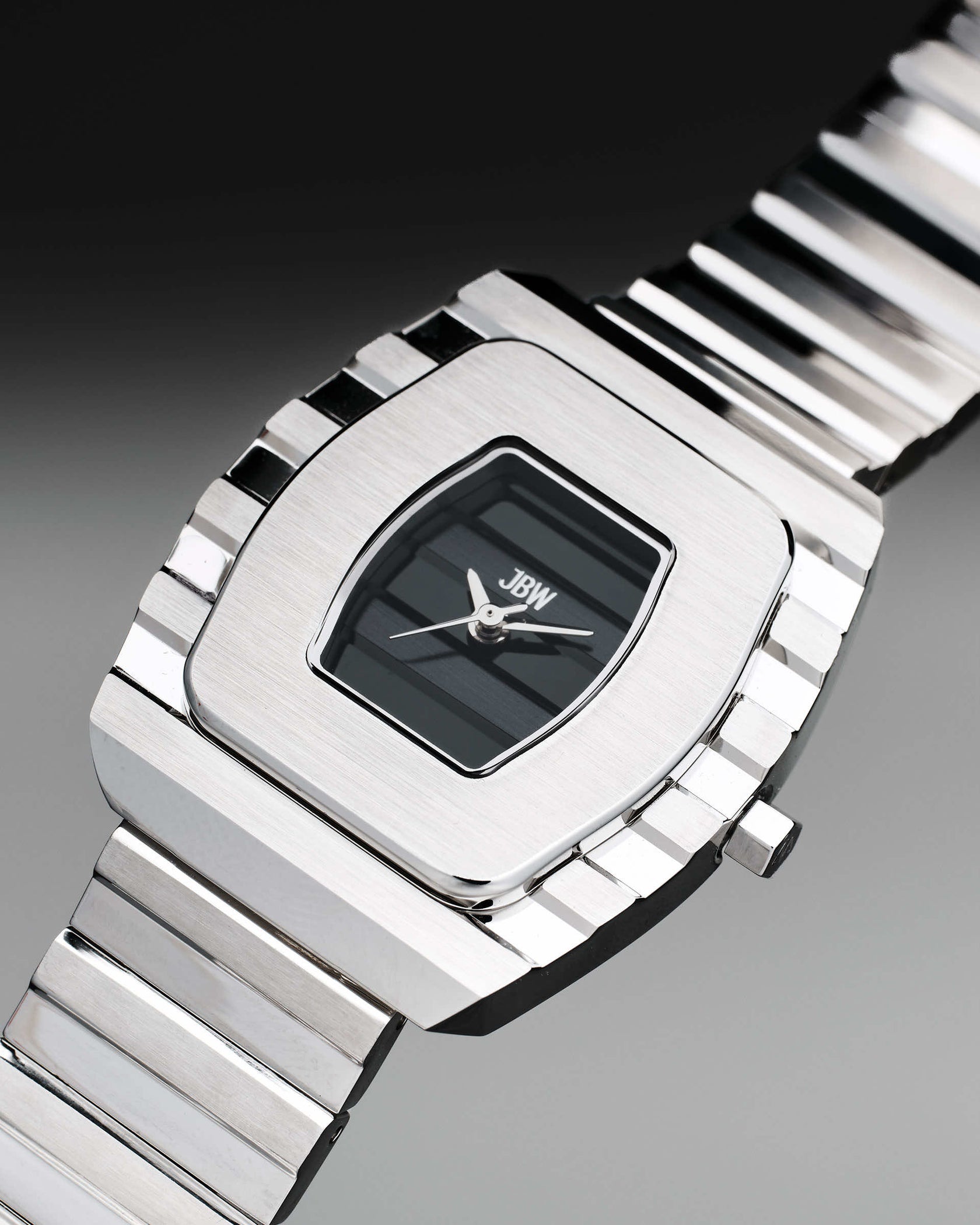 A close-up of the JBW Watches Atlas | J6403D, a women’s 34mm stainless steel watch featuring a rectangular black face, silver hands, and a metal link band, with JBW branding on the dial against a gradient background.