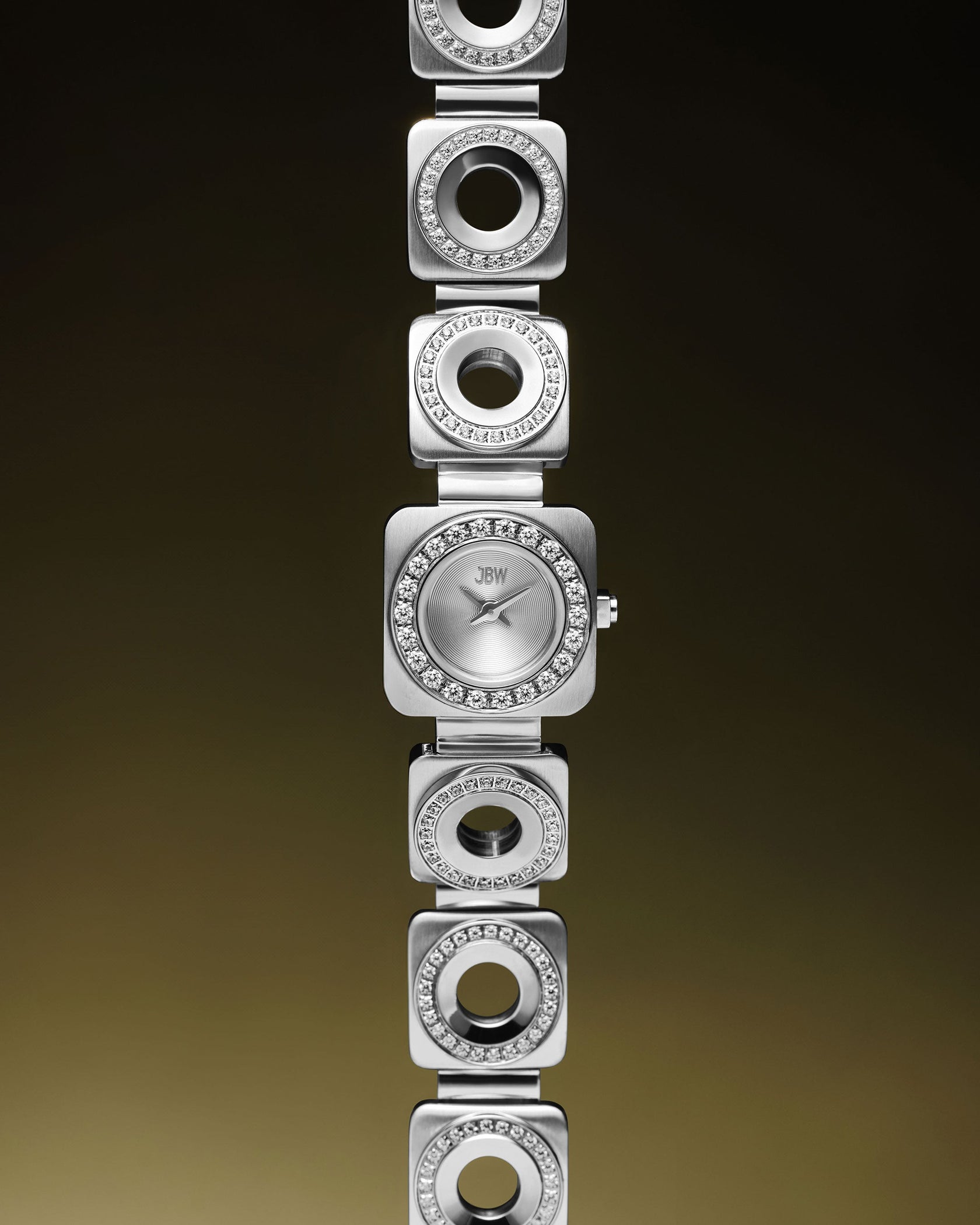 The Chasm Petite (Sample Sale) | J6401B-GA by JBW Watches is a silver stainless steel watch with a square face, premium crystal accents, and a unique bracelet of alternating solid/open links, shown against a gradient brown background.