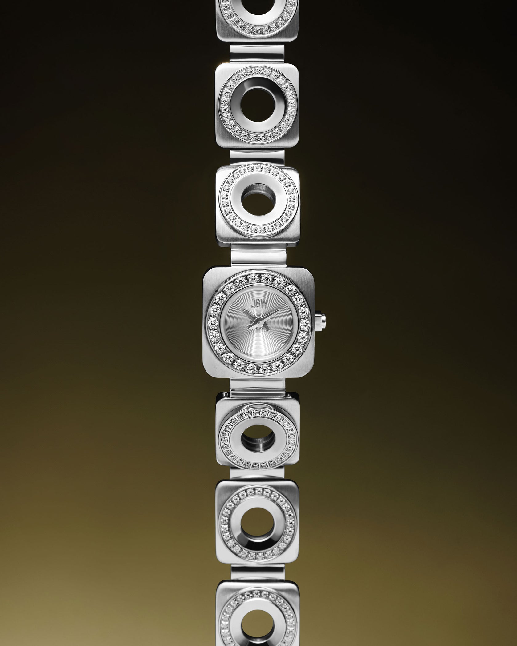 The Chasm Petite | J6401B by JBW Watches features a silver stainless steel square face, circular crystal accents, and alternating square and circular crystal-embellished links, all set against a dark gradient background.