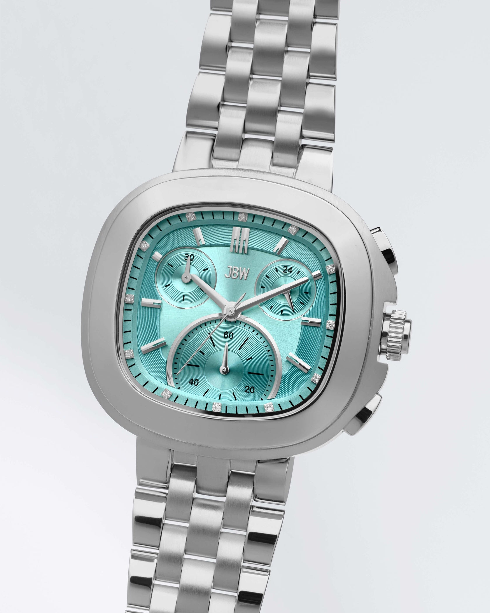 The JBW Watches Coast | J6397G is a silver stainless steel chronograph wristwatch with a turquoise face, three subdials, and silver hour markers, set against a light gray background.