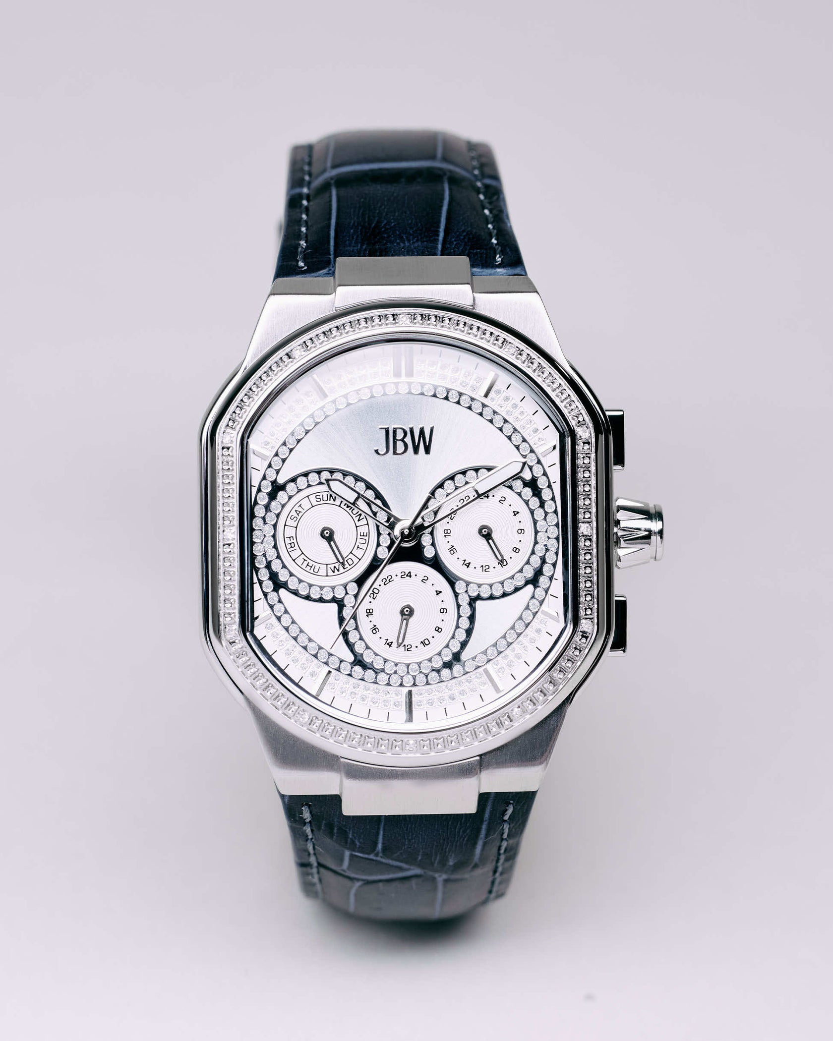 The JBW Orion | J6408A is a diamond watch with a silver bezel, black leather strap, three subdials on a white, diamond-accented face, multiple time functions, and a right-side crown.