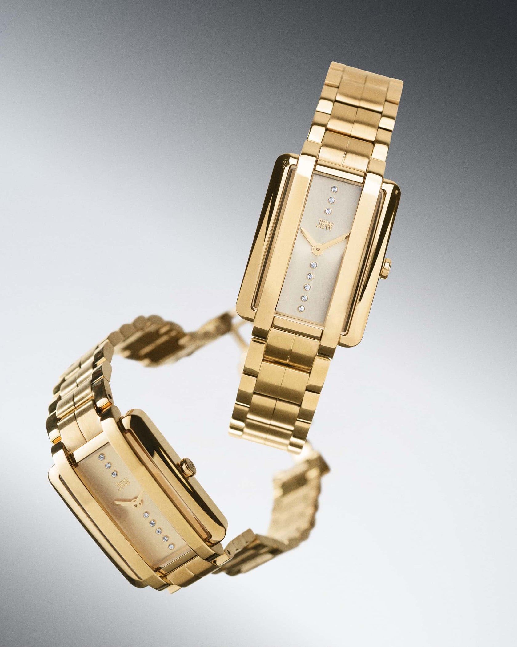 Two luxury JBW Watches, including the Mink Petite | J6395A, float against a gradient backdrop. Their rectangular faces feature minimalist designs with a vertical row of lab grown diamonds and elegant link bands.