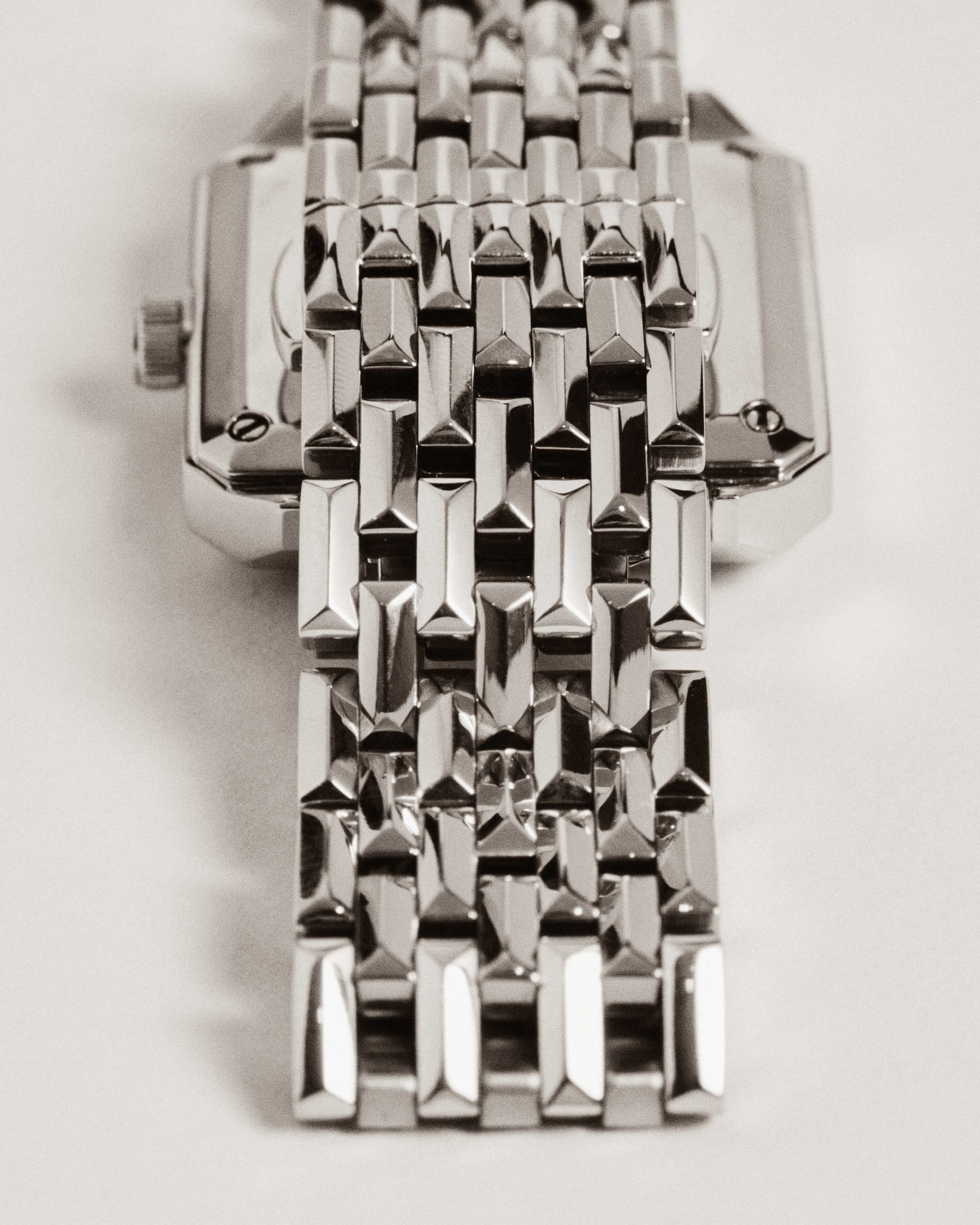 Close-up of the Astra | J6410A by JBW Watches, a silver square silhouette watch with a rectangular face, reflective geometric link bracelet, and Swiss quartz movement, photographed from above on a light background.