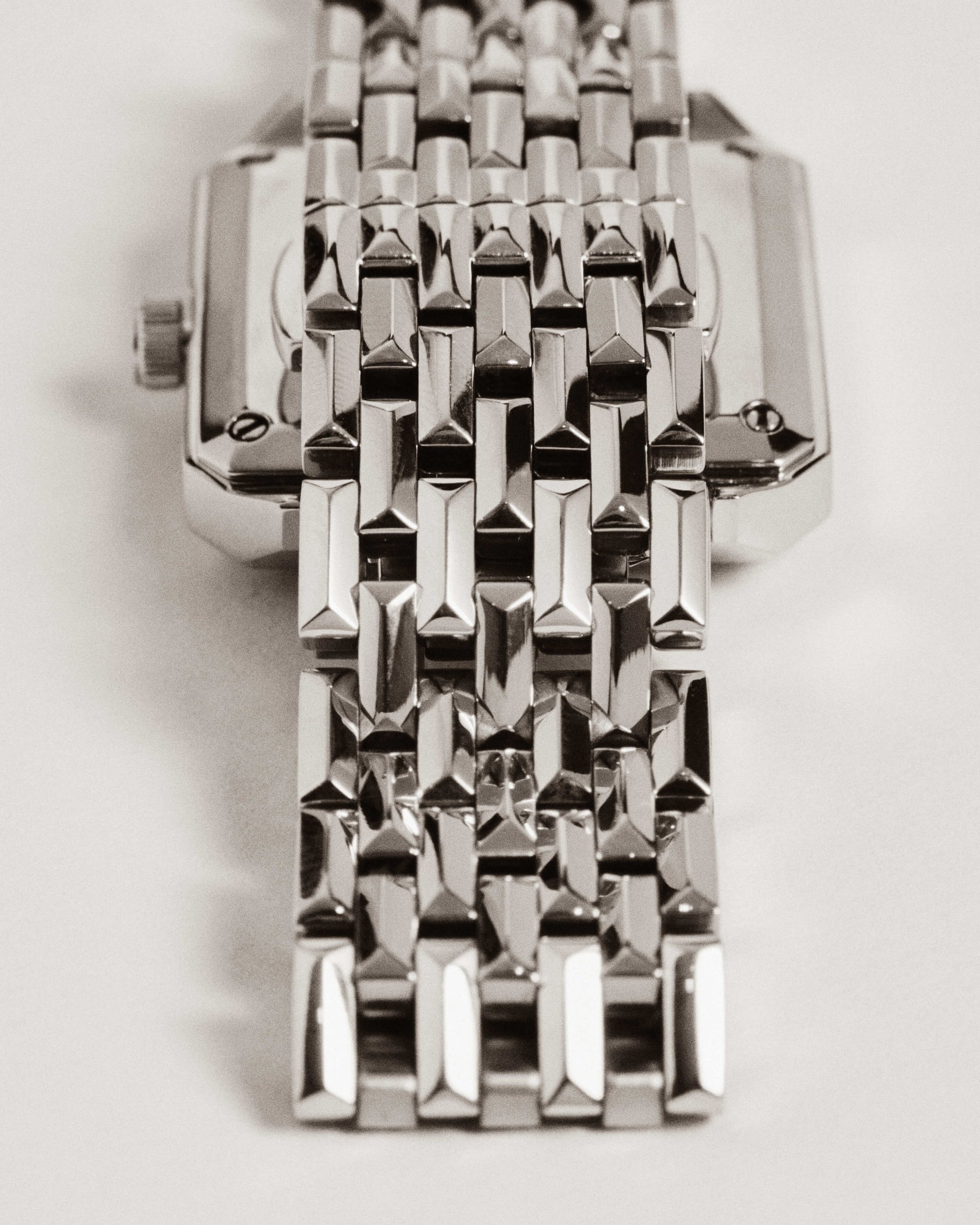 Close-up of the Astra | J6410A by JBW Watches, a silver square silhouette watch with a rectangular face, reflective geometric link bracelet, and Swiss quartz movement, photographed from above on a light background.
