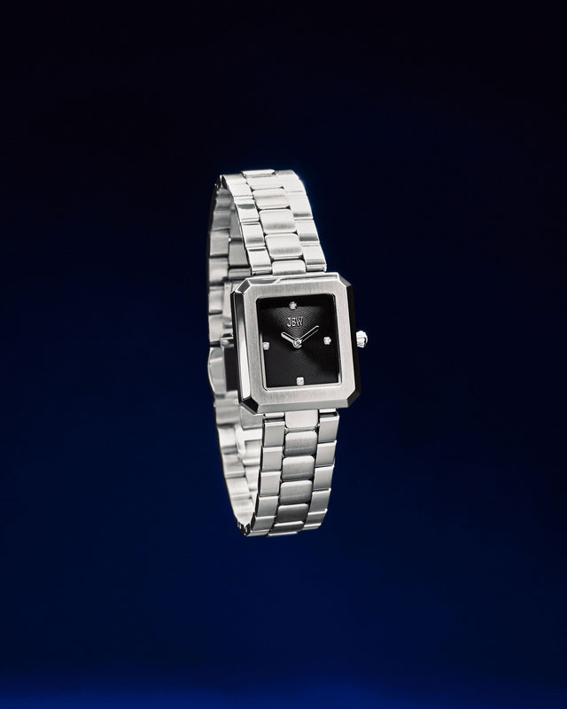The JBW Watches Arc Single | J6390G features a rectangular case, black face, four lab-grown diamond markers, and a silver metal link band. Displayed on a white background, this stylish timepiece offers gender-neutral appeal.