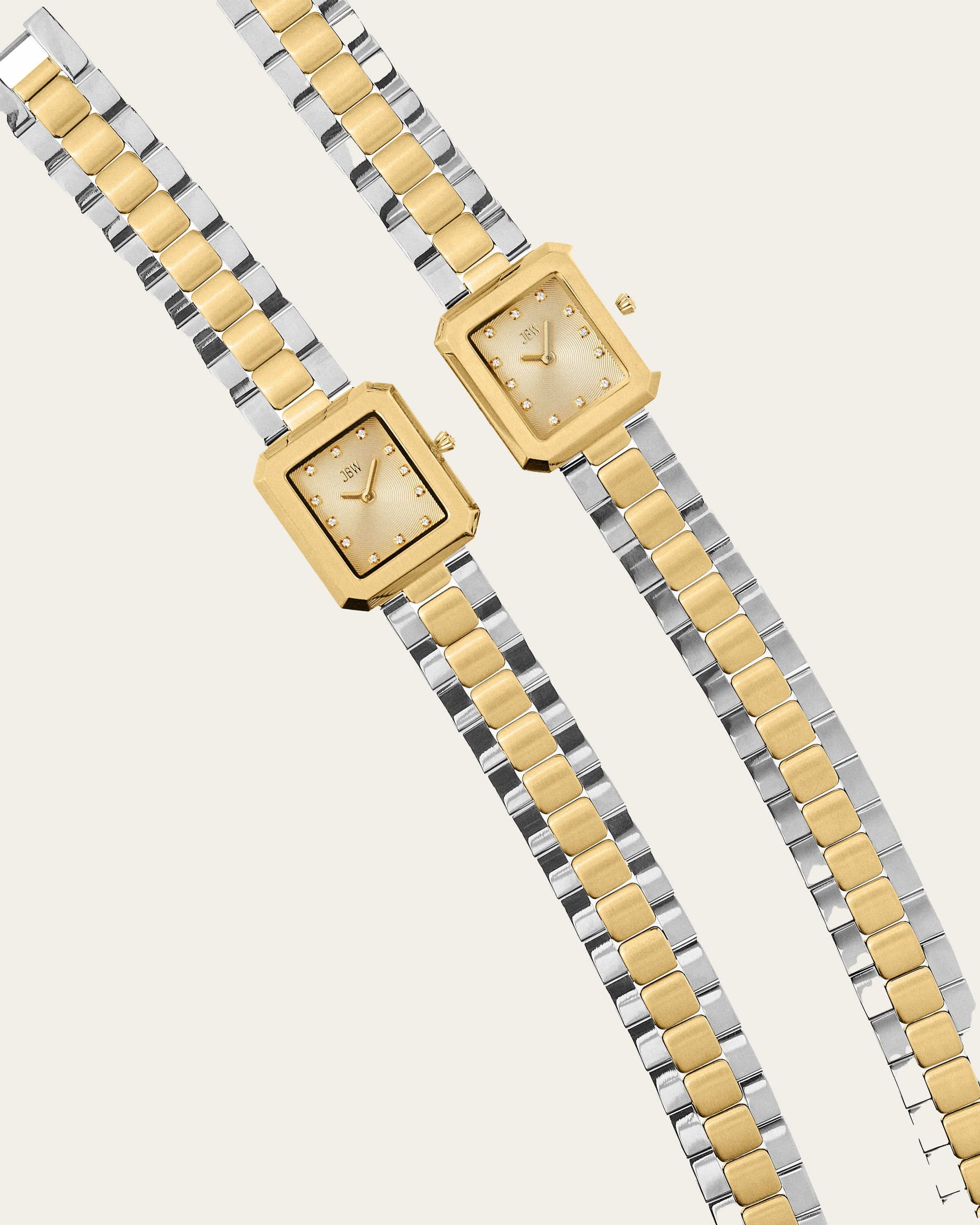 Two rectangular JBW Watches Arc Double (Sample Sale) wristwatches with gold and silver metal bands and gold faces are displayed diagonally side by side on a light background.