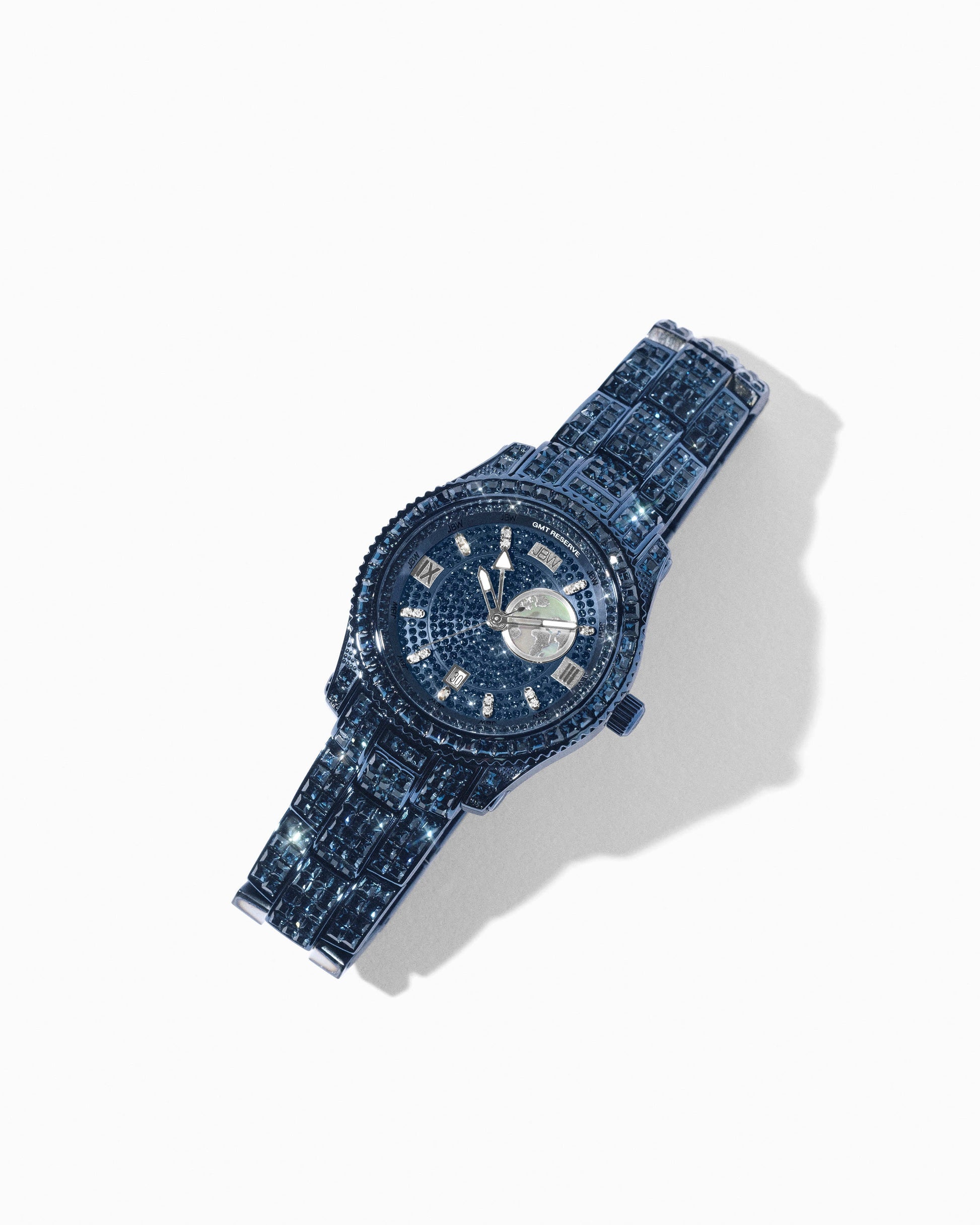 The RESERVE Bleu 39 | R6393A-GA by JBW Watches features sapphire blue crystals and a detailed face. Its sparkling band shines on a white background, combining elegance with the precision of Swiss GMT movement in this Grade A Sample Sale piece.